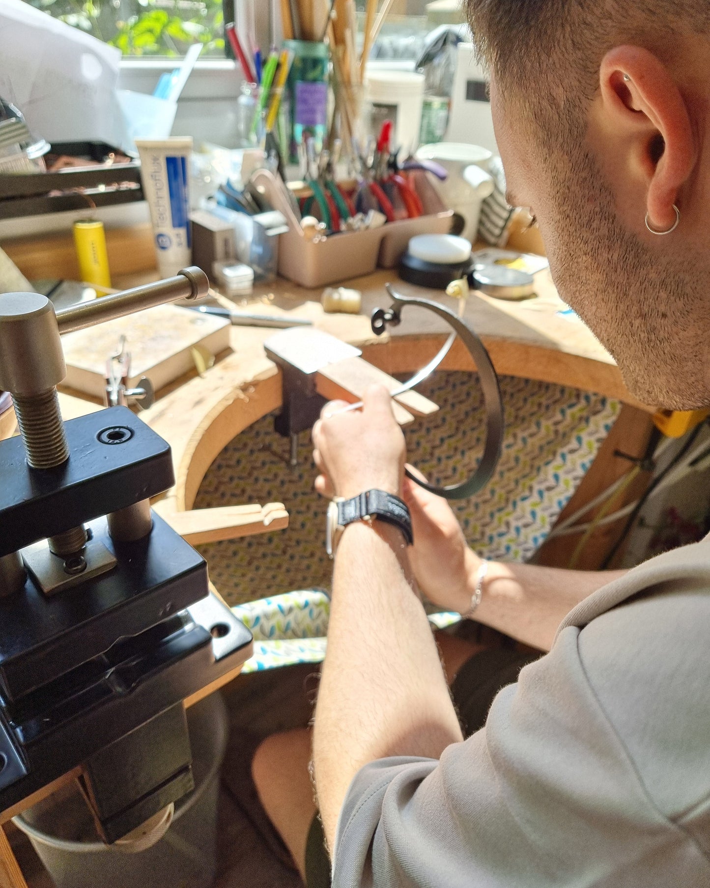 Man at jewellers bench with piercing saw